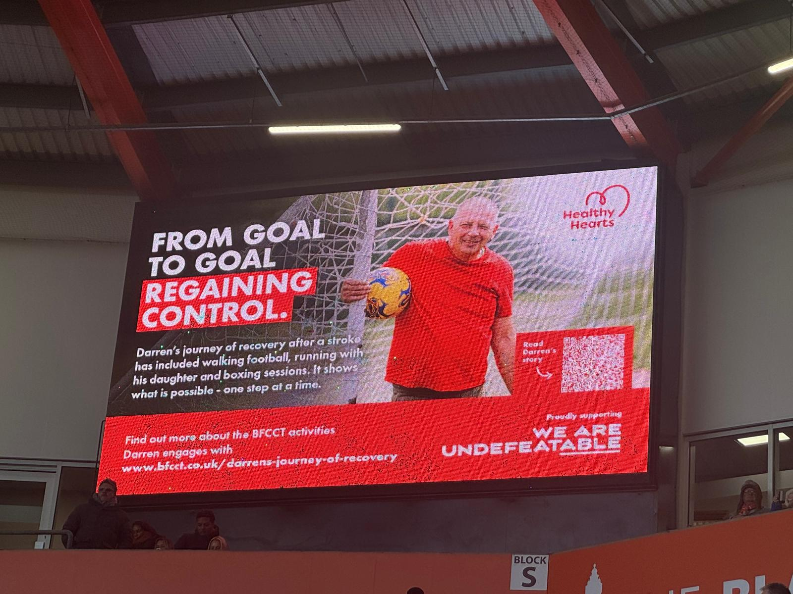 An advertisement on the large digital screen at Blackpool FC's stadium, featuring Darren's story.