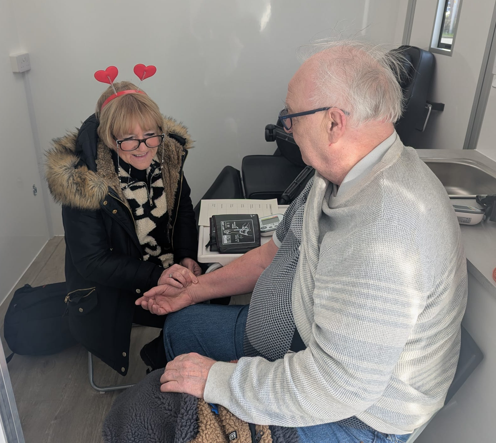 A man having his blood pressure checked by a lady in the Harri van.